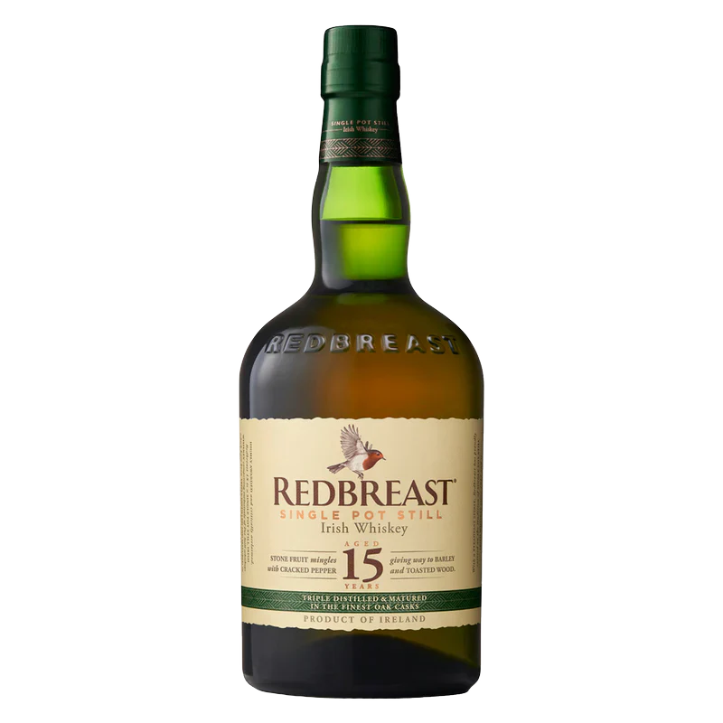 A bottle of Redbreast 15 Year Old Irish whiskey with a green glass body, cream label, and gold and red accents. The label displays a bird illustration and text highlighting this renowned Redbreast whiskey.