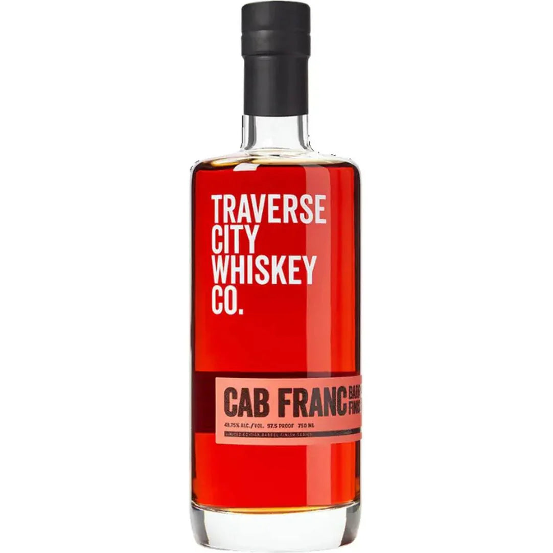 A bottle of Traverse City Whiskey Co. Cab Franc Barrel Finish features a black cap, bold red and white label on clear glass, and displays its rich amber whiskey.