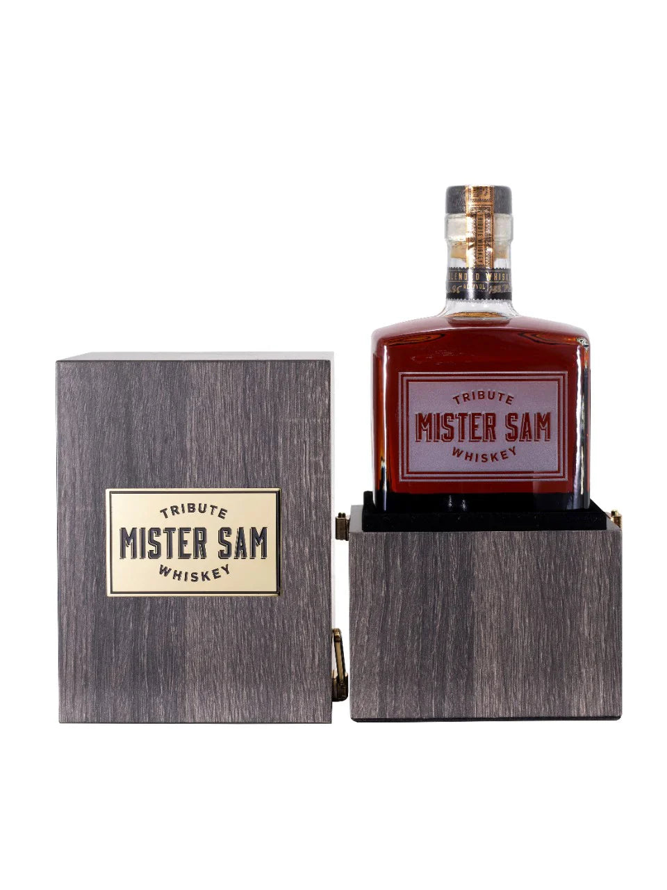 A bottle of Sazerac Mister Sam Tribute Whiskey Second Edition, a cask strength blend, comes in a wooden box with a gold label. The open box displays the bottle featuring its bold red and gold “Mister Sam Tribute Whiskey” label.