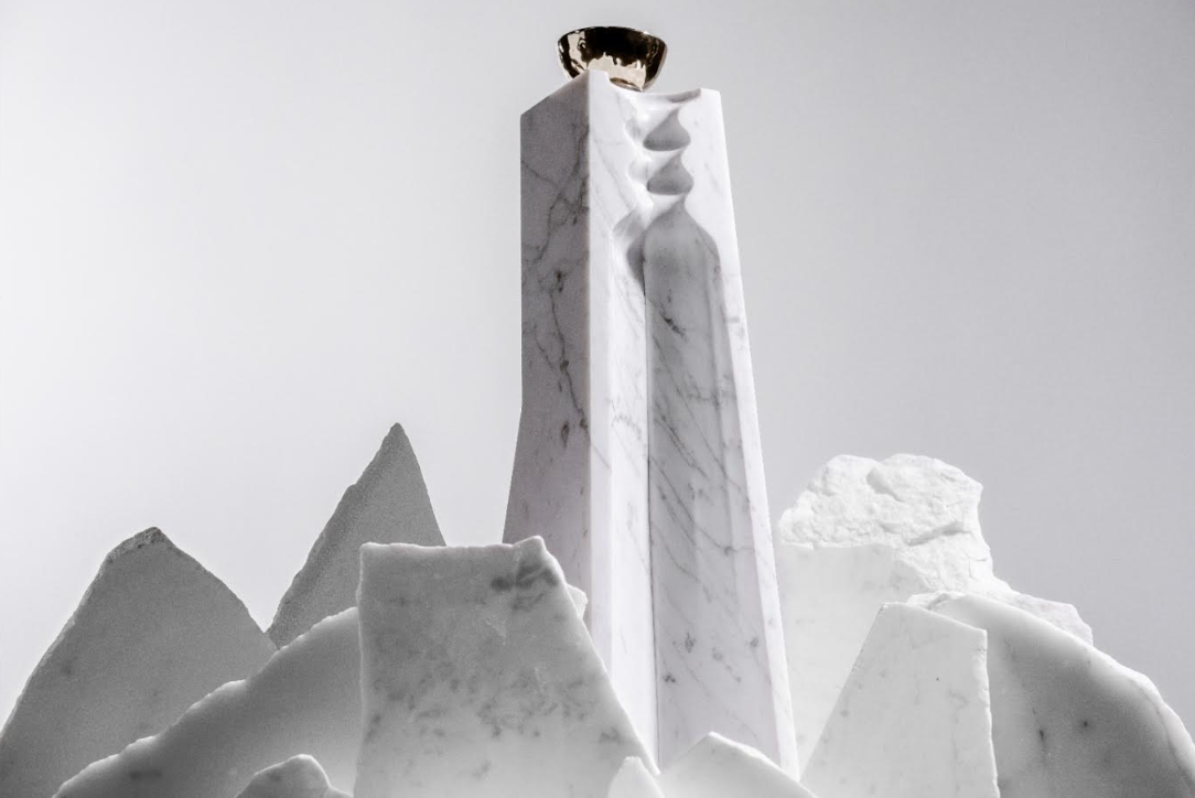 A tall, white marble sculpture with graceful curves and a metallic cup reflects the elegance of Volcan De Mi Tierra Coleccion I Hacienda La Gavilana Anejo Tequila, its refined form highlighted against a light backdrop.