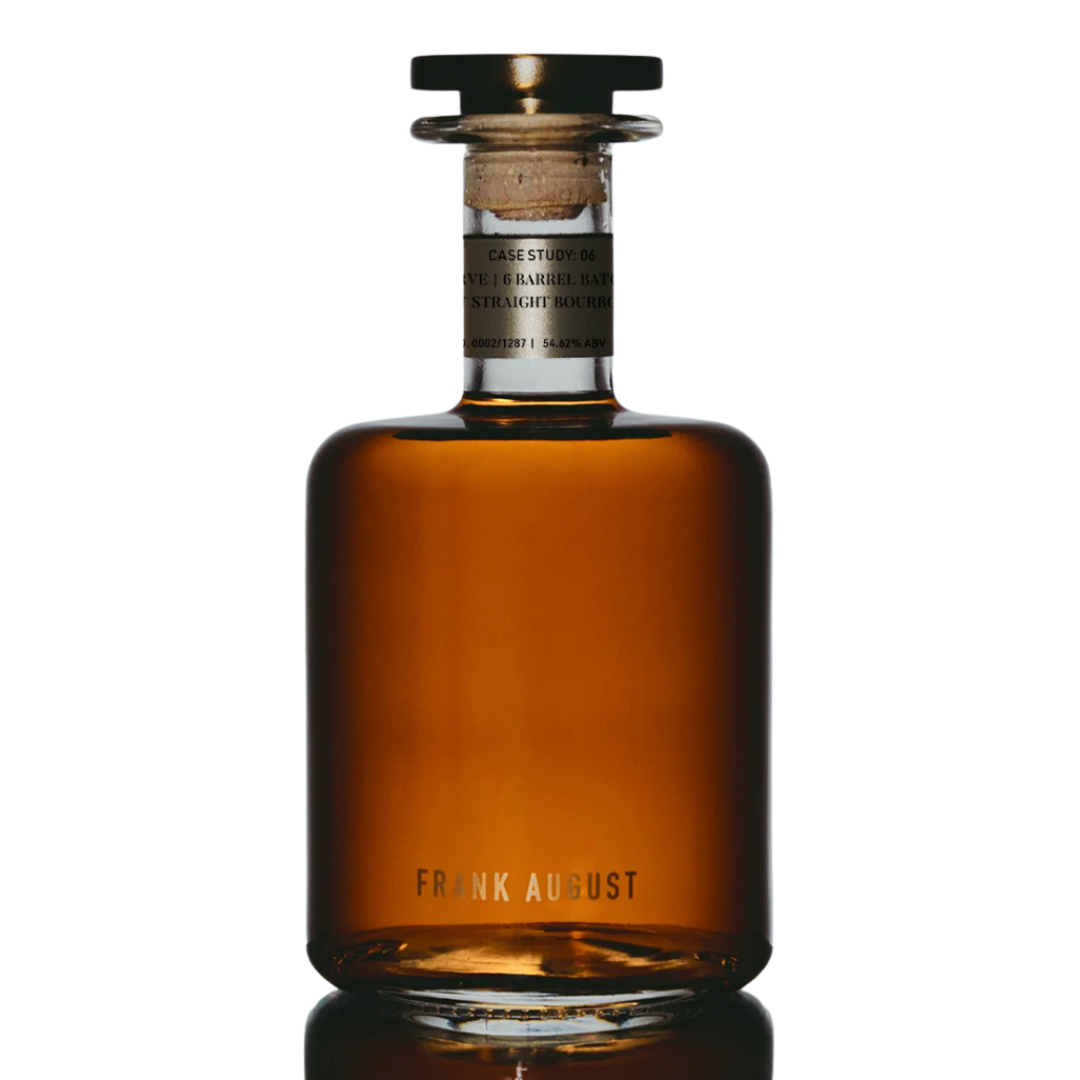 A clear glass bottle of Frank August Case Study: 06 Legacy Reserve Kentucky Straight Bourbon Whiskey, with amber liquid, a short neck, round wooden stopper, "Frank August" at the base, and a small label near the top.