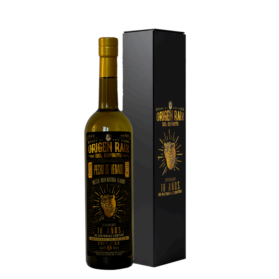 A dark glass bottle of Origen Raiz Pecho de Venado Anniversary Edition Mezcal (PRE-ORDER) stands beside a matching black and gold box, featuring gold lettering, a deer head design, and the label "10 años de producción continua.